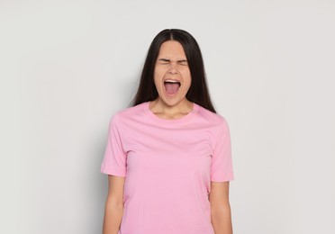Photo of Aggressive young woman shouting on light grey background