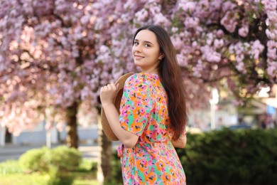 Beautiful woman with straw hat near blossoming tree on spring day