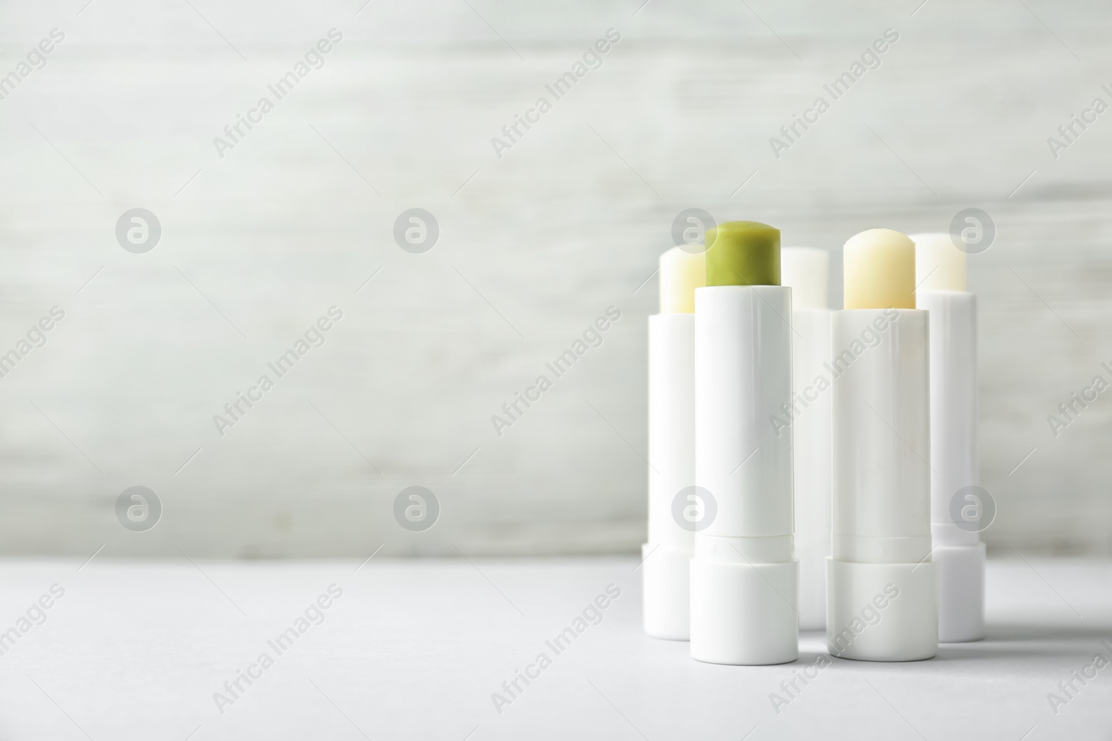 Photo of Hygienic lipsticks on table against light background