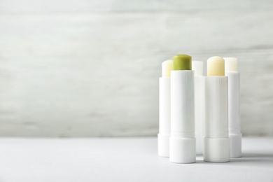 Hygienic lipsticks on table against light background