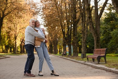 Photo of Portrait of affectionate senior couple in autumn park, space for text