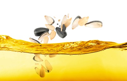 Sunflower seeds falling into cooking oil on white background