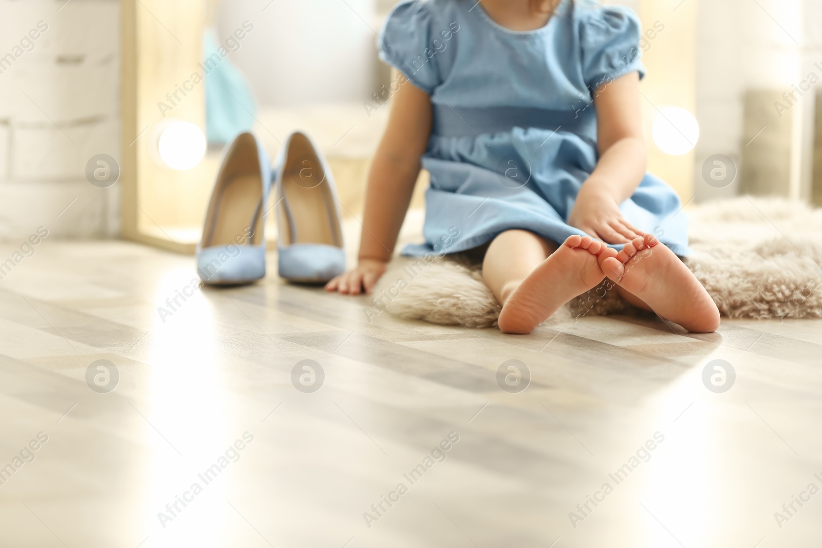 Photo of Cute little girl sitting on floor at home, closeup