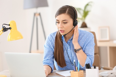 Photo of Young woman talking on phone through headset at workplace