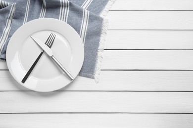 Photo of Clean plate with shiny silver cutlery on white wooden table, flat lay. Space for text