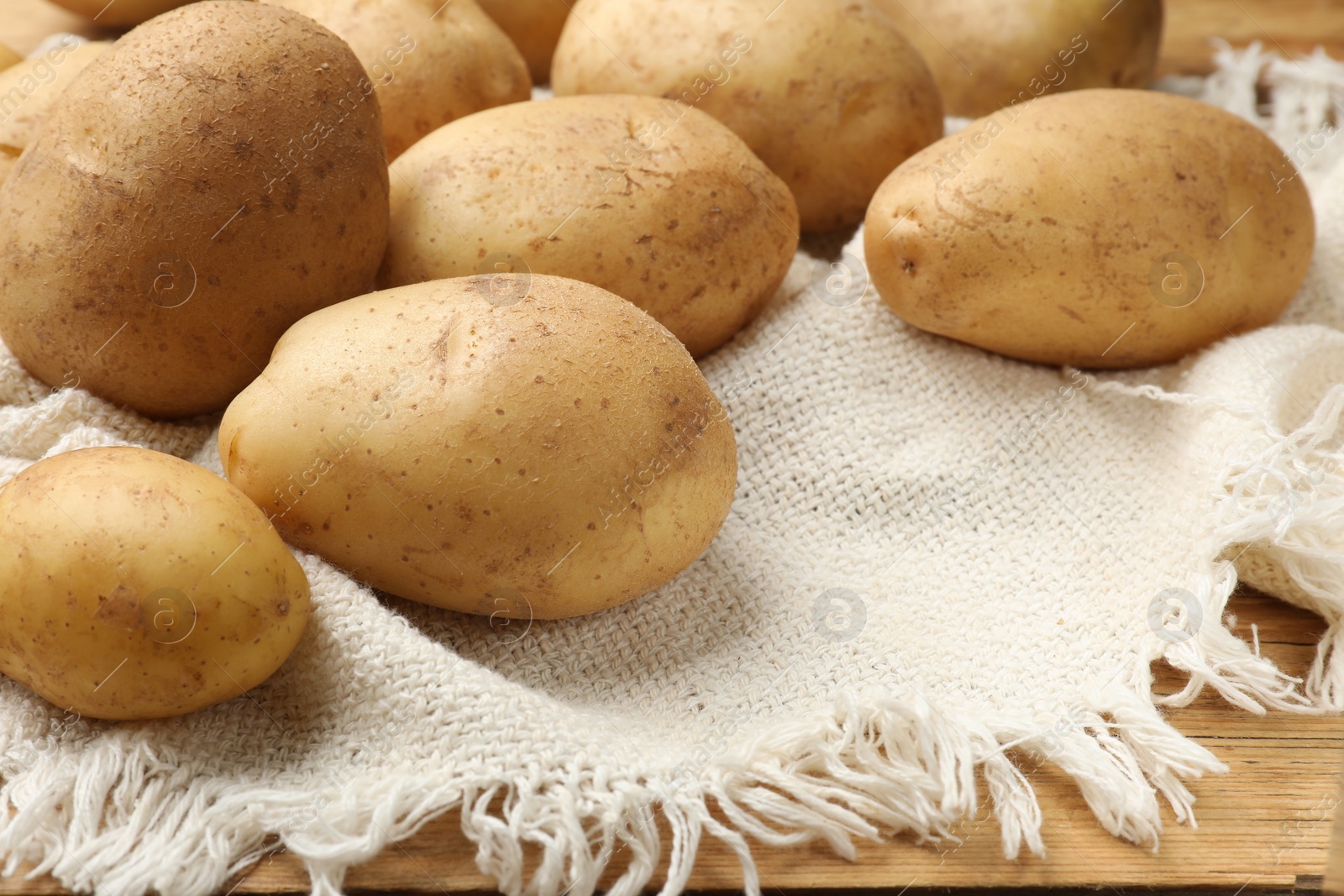 Photo of Raw fresh potatoes and napkin on wooden table