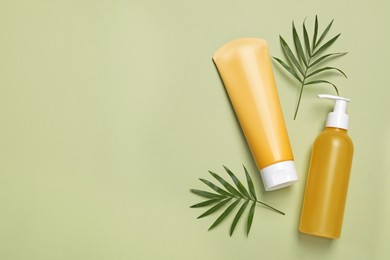 Photo of Different cleansers and leaves on olive background, flat lay with space for text. Cosmetic product