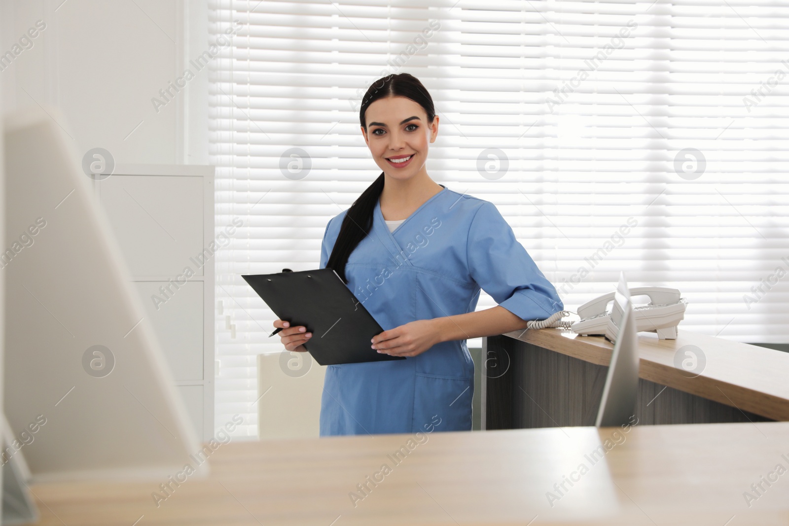 Photo of Receptionist with clipboard at countertop in hospital