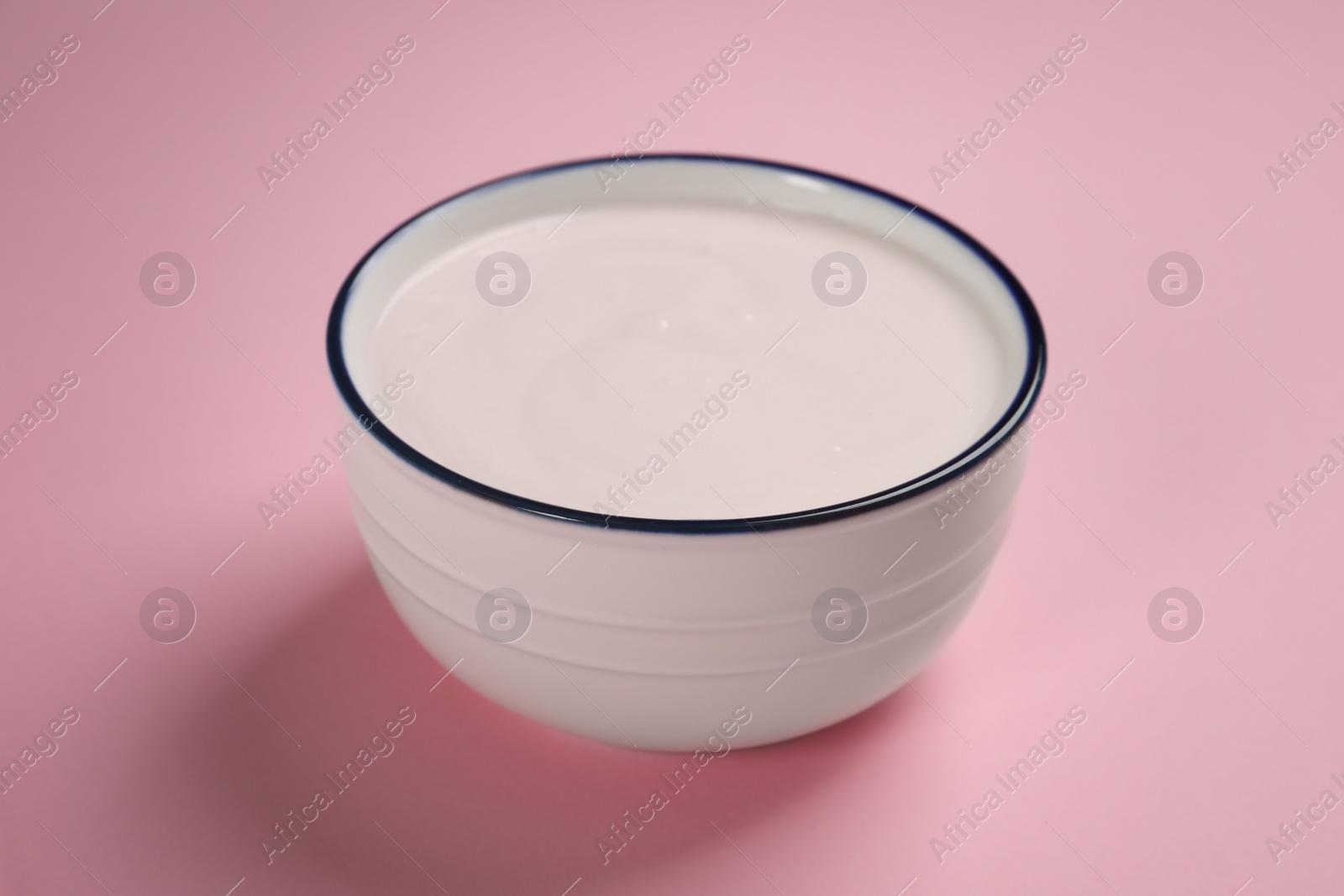 Photo of Bowl of tasty yogurt on pink background