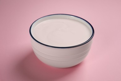 Photo of Bowl of tasty yogurt on pink background