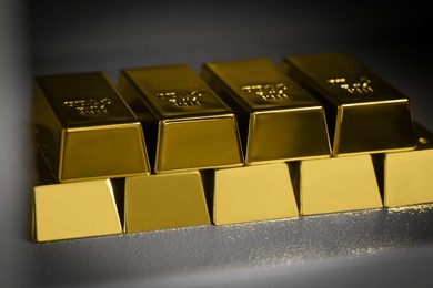 Photo of Many gold bars on light grey textured table, closeup