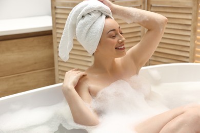 Photo of Happy woman taking bath with foam in tub indoors, space for text