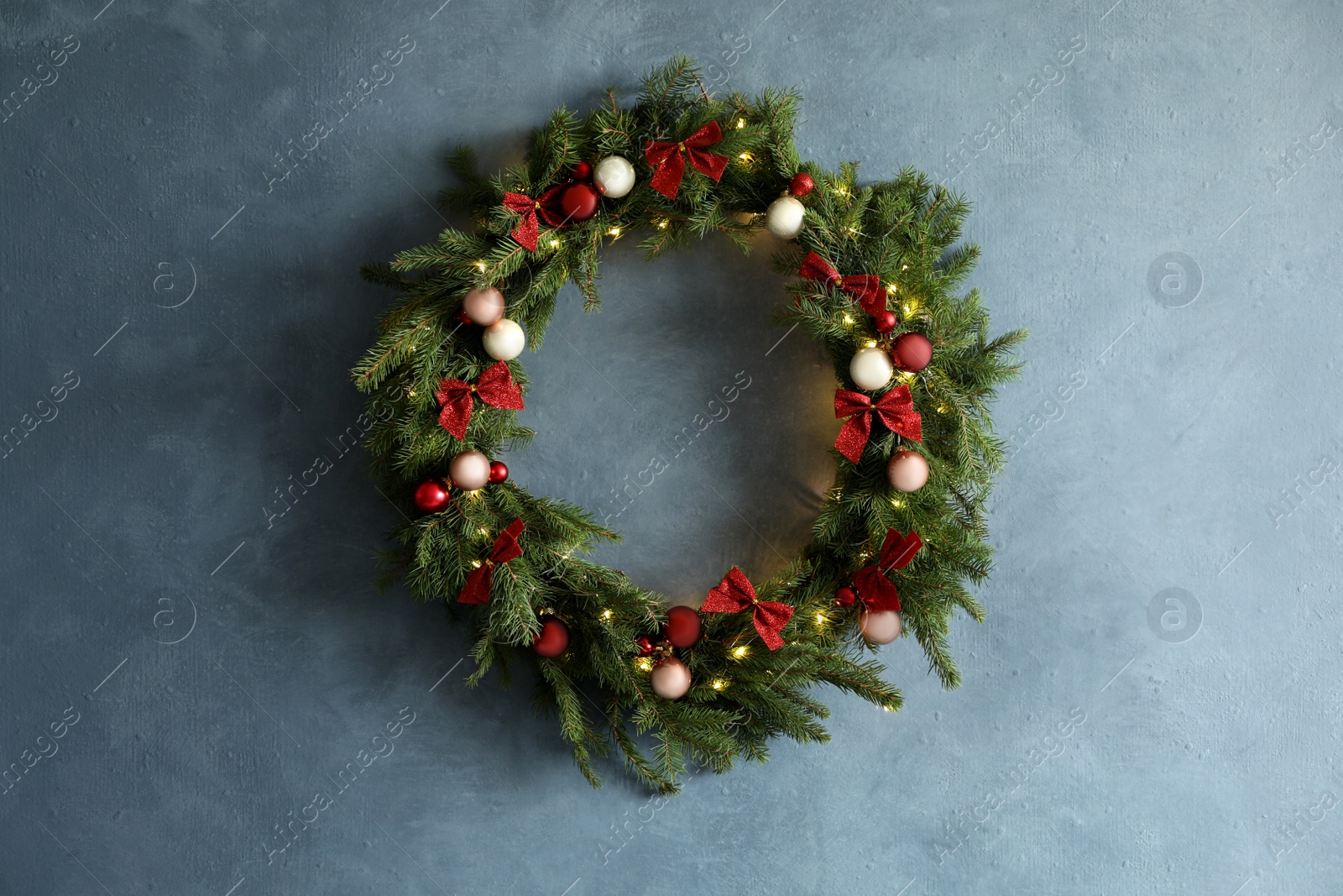 Photo of Beautiful Christmas wreath with festive decor on blue wall