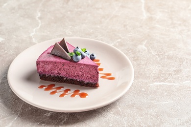 Photo of Plate with piece of tasty blueberry cake on gray table. Space for text