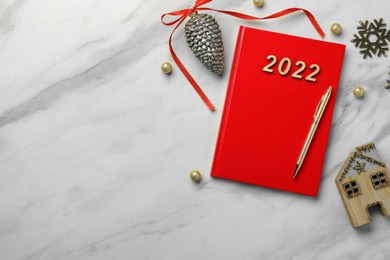 Photo of Red planner and Christmas decor on white marble background, flat lay with space for text. 2022 New Year aims