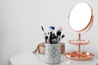 Photo of Makeup brushes in holder on table against light background