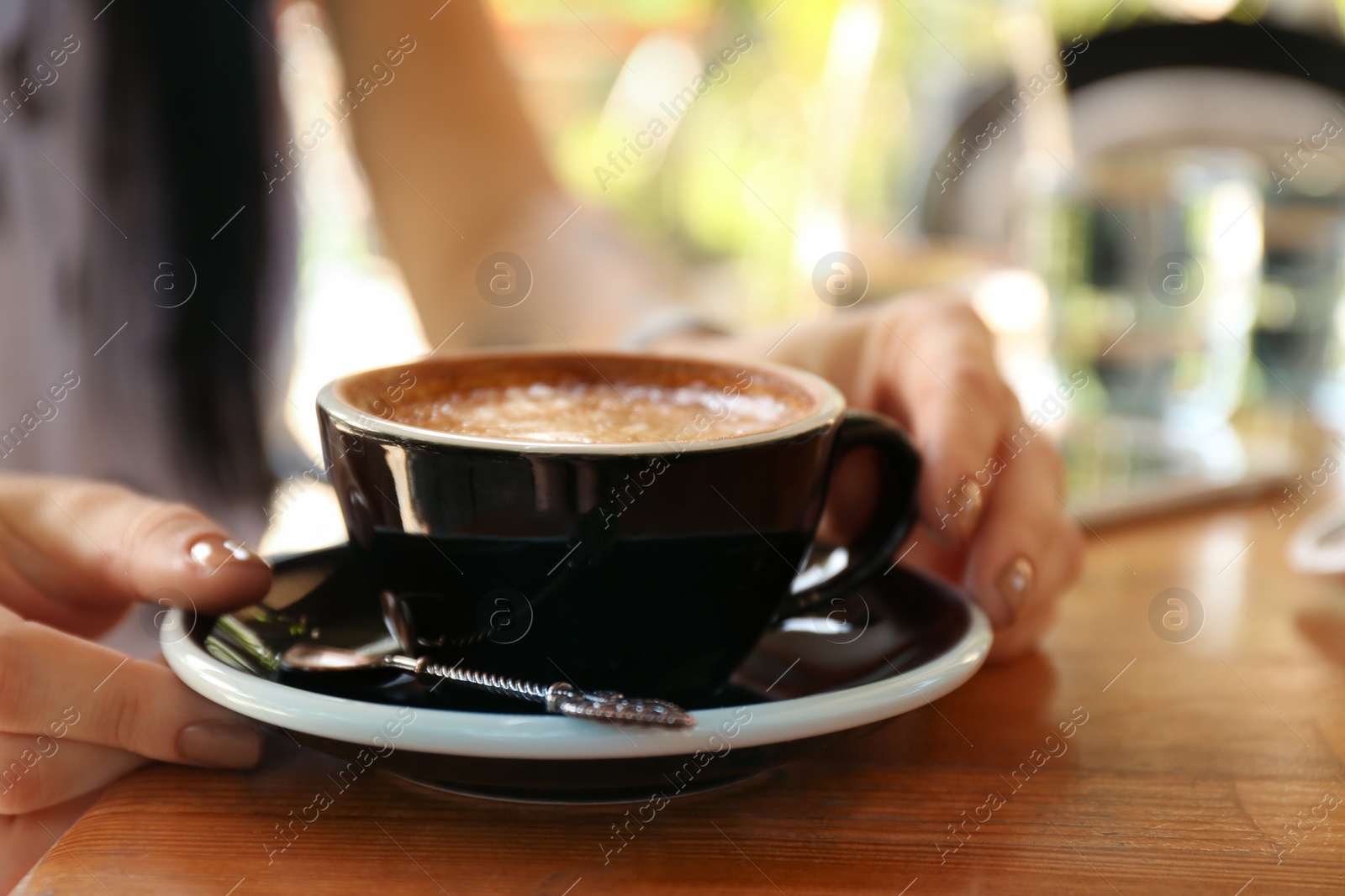 Photo of Woman with cup of fresh aromatic coffee at table, closeup