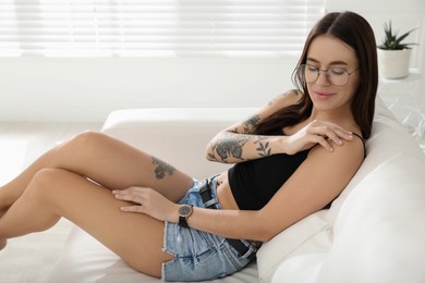 Photo of Beautiful woman with tattoos on body resting in living room