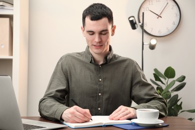 Man taking notes at wooden table in office