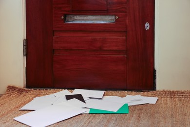 Many envelopes on rug near wooden door indoors