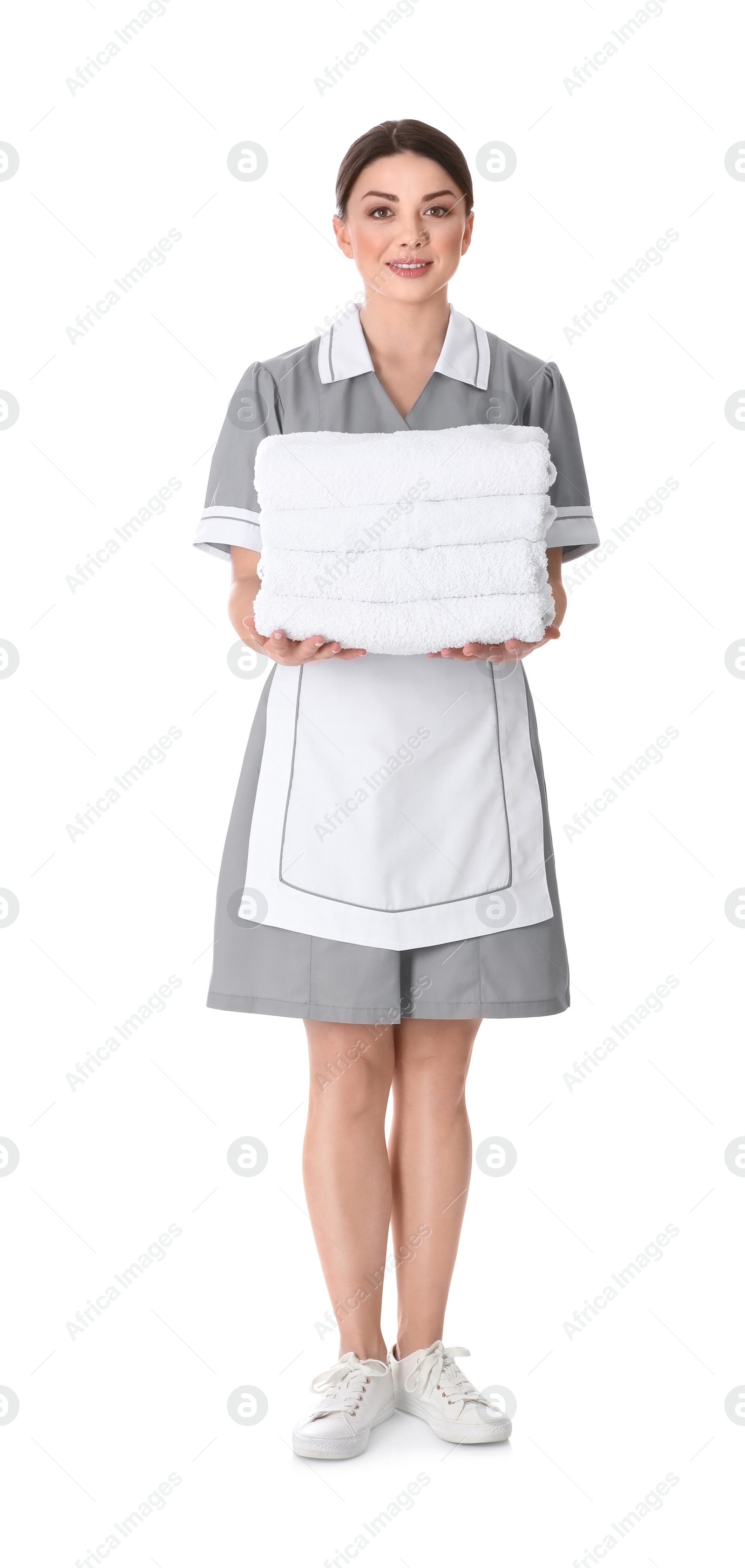 Photo of Young chambermaid holding stack of fresh towels on white background