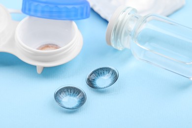 Photo of Case with color contact lenses and bottle on light blue background