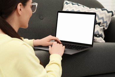 Woman using laptop on couch at home, selective focus