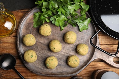 Photo of Raw falafel balls and ingredients on wooden table, flat lay