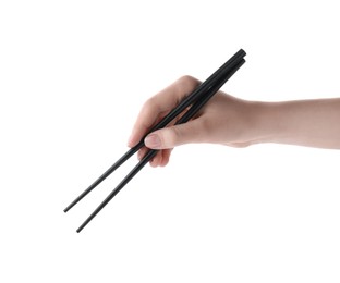 Woman holding pair of black chopsticks on white background, closeup