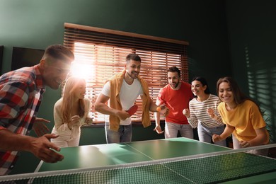 Happy friends playing ping pong together indoors