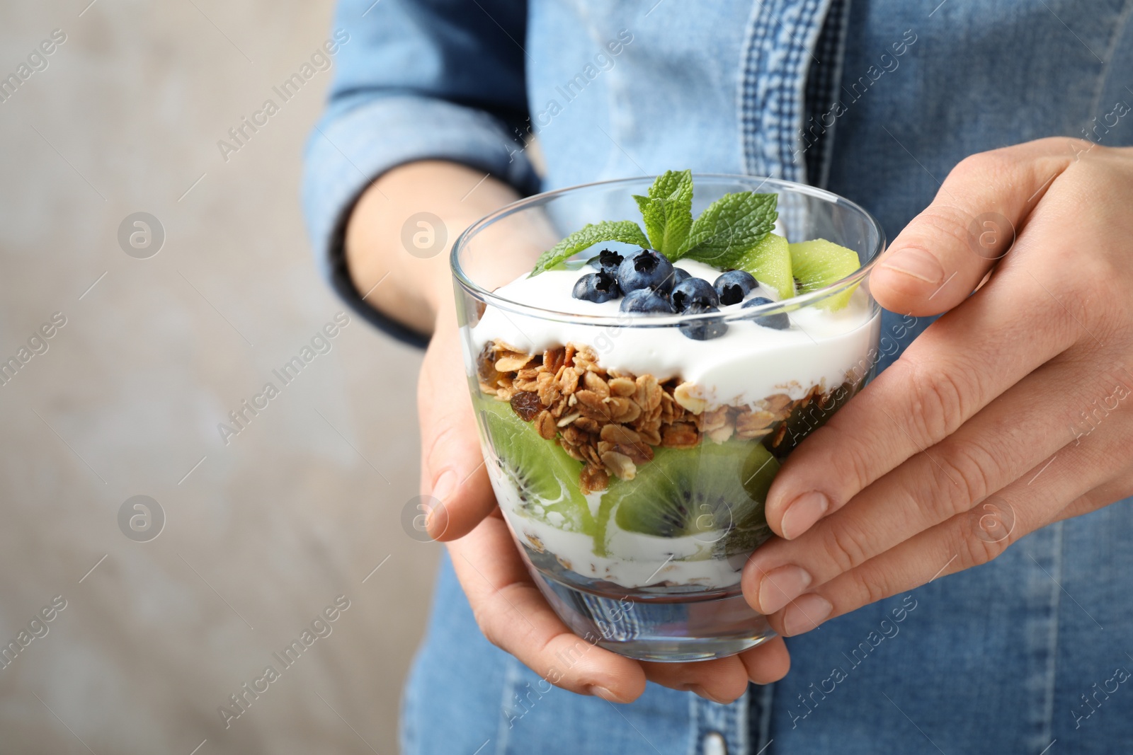 Photo of Woman holding glass of tasty homemade granola dessert, closeup. Healthy breakfast