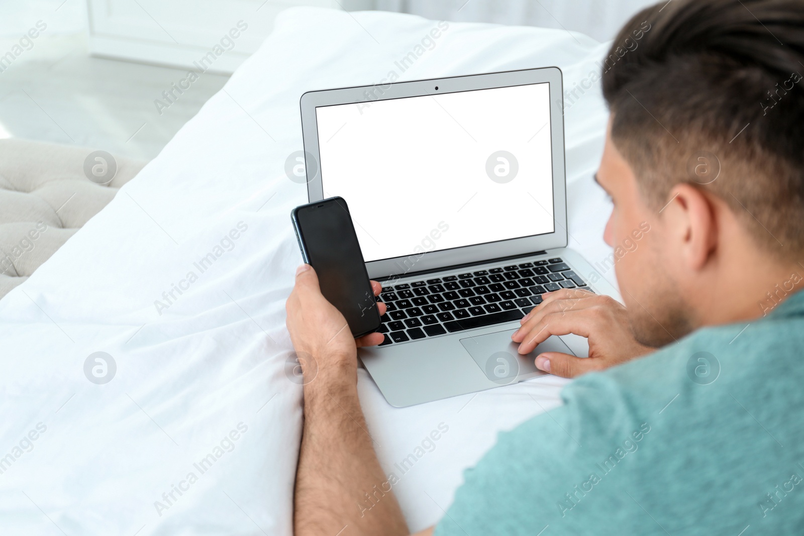 Photo of Man with smartphone and modern laptop at home, closeup