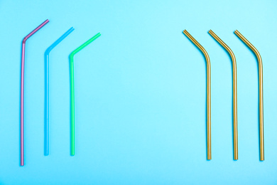 Photo of Flat lay composition with plastic and metal drinking straws on light blue background, space for text. Recycling concept