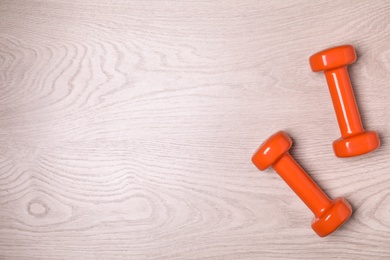 Vinyl dumbbells and space for text on wooden background, flat lay