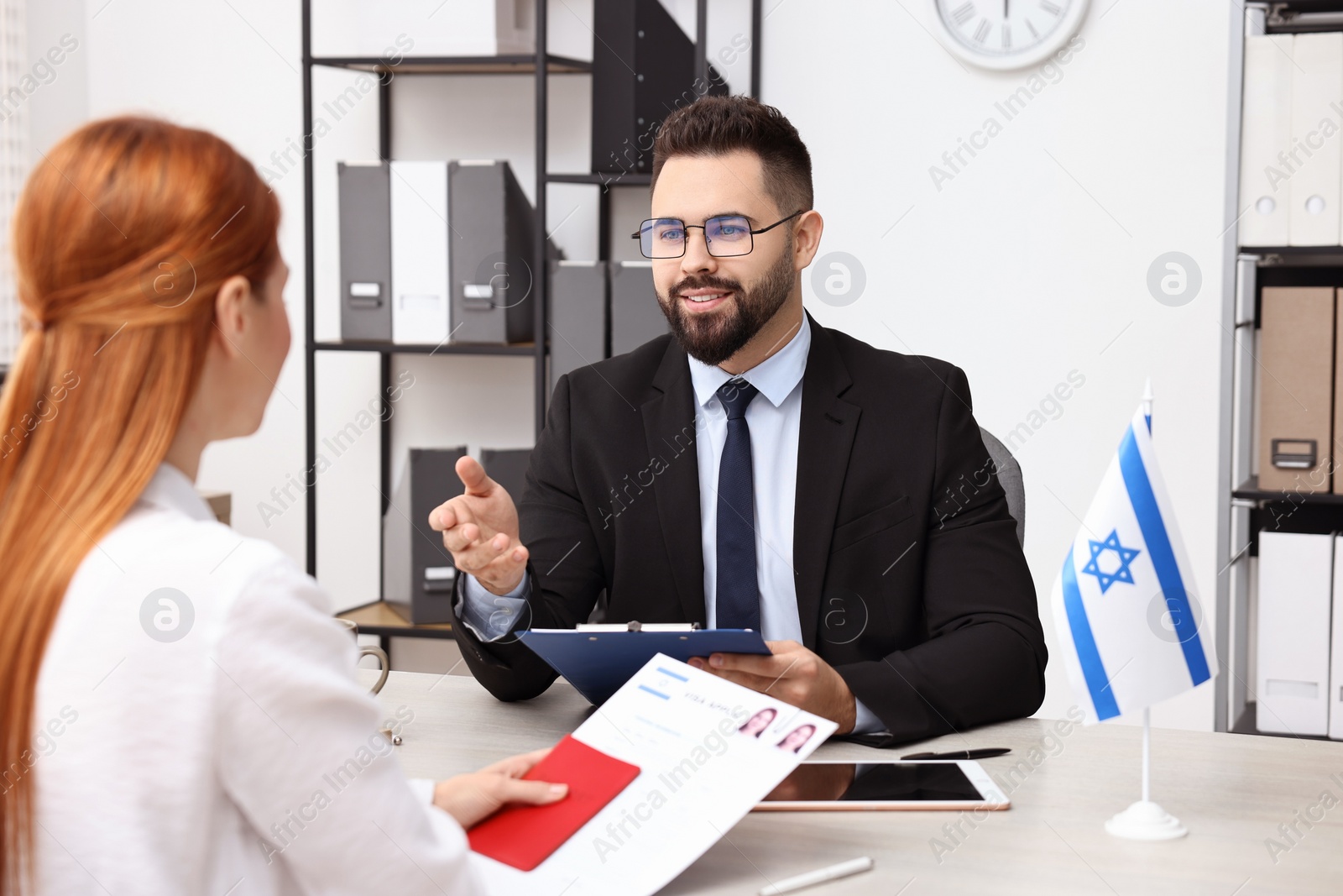 Photo of Smiling embassy worker consulting woman about immigration to Israel in office