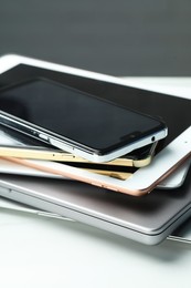 Photo of Stack of electronic devices on white table, closeup