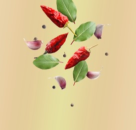 Image of Bay leaves, garlic cloves, black and dry red pepper falling on beige background