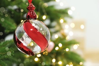 Photo of Beautiful holiday bauble hanging on Christmas tree, closeup. Space for text