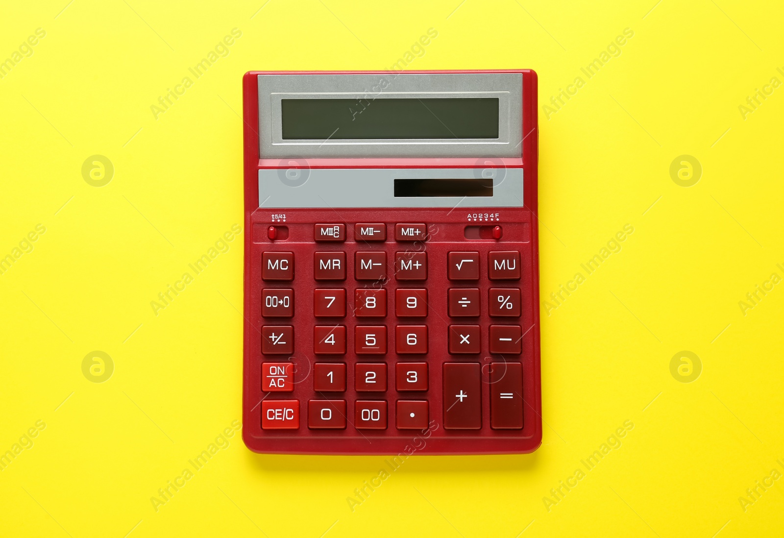 Photo of Red calculator on yellow background, top view