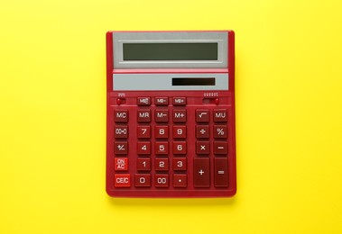 Red calculator on yellow background, top view