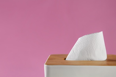 Photo of Holder with paper tissues on pink background, closeup. Space for text