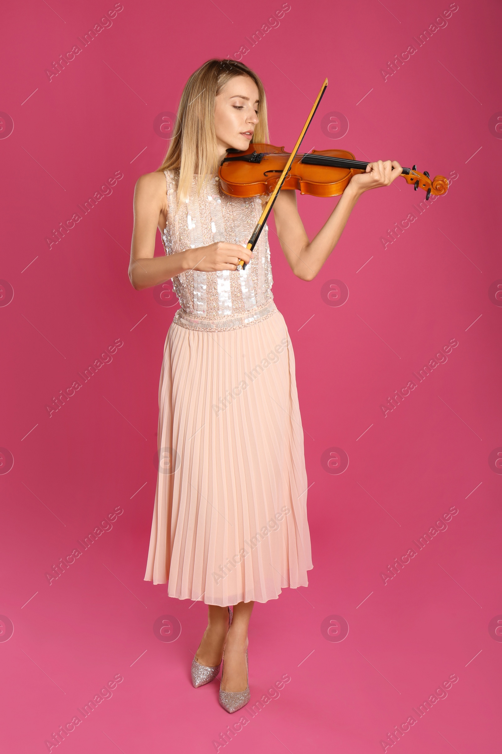 Photo of Beautiful woman playing violin on pink background