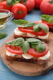 Photo of Delicious Caprese sandwiches with mozzarella, tomatoes and basil on light blue wooden table