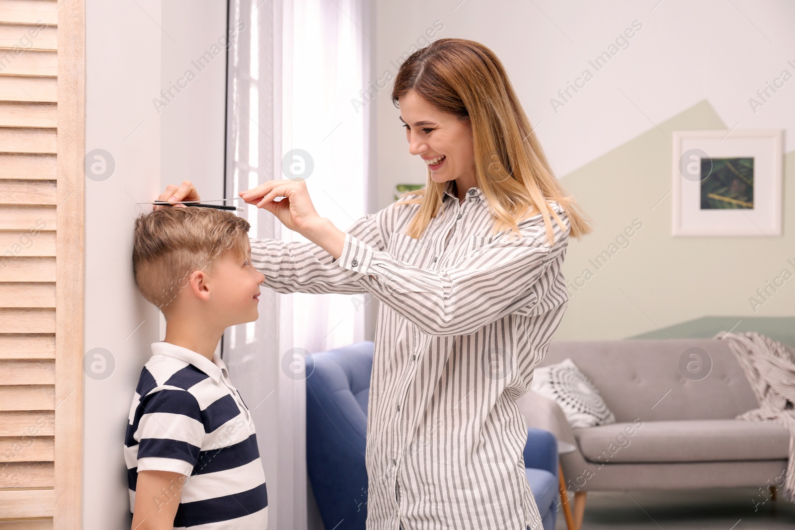 Photo of Young woman measuring her son's height at home