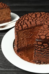 Photo of Delicious chocolate truffle cake on black wooden table, closeup