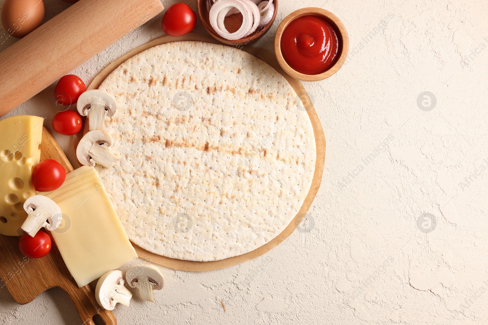 Photo of Pizza base, ketchup and products on light textured table, flat lay. Space for text