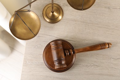 Photo of Law concept. Judge's mallet and scales of justice on light wooden table indoors, top view