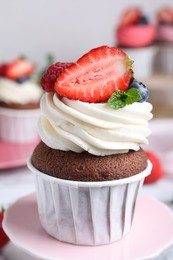 Photo of Delicious cupcake with cream and berries on stand, closeup