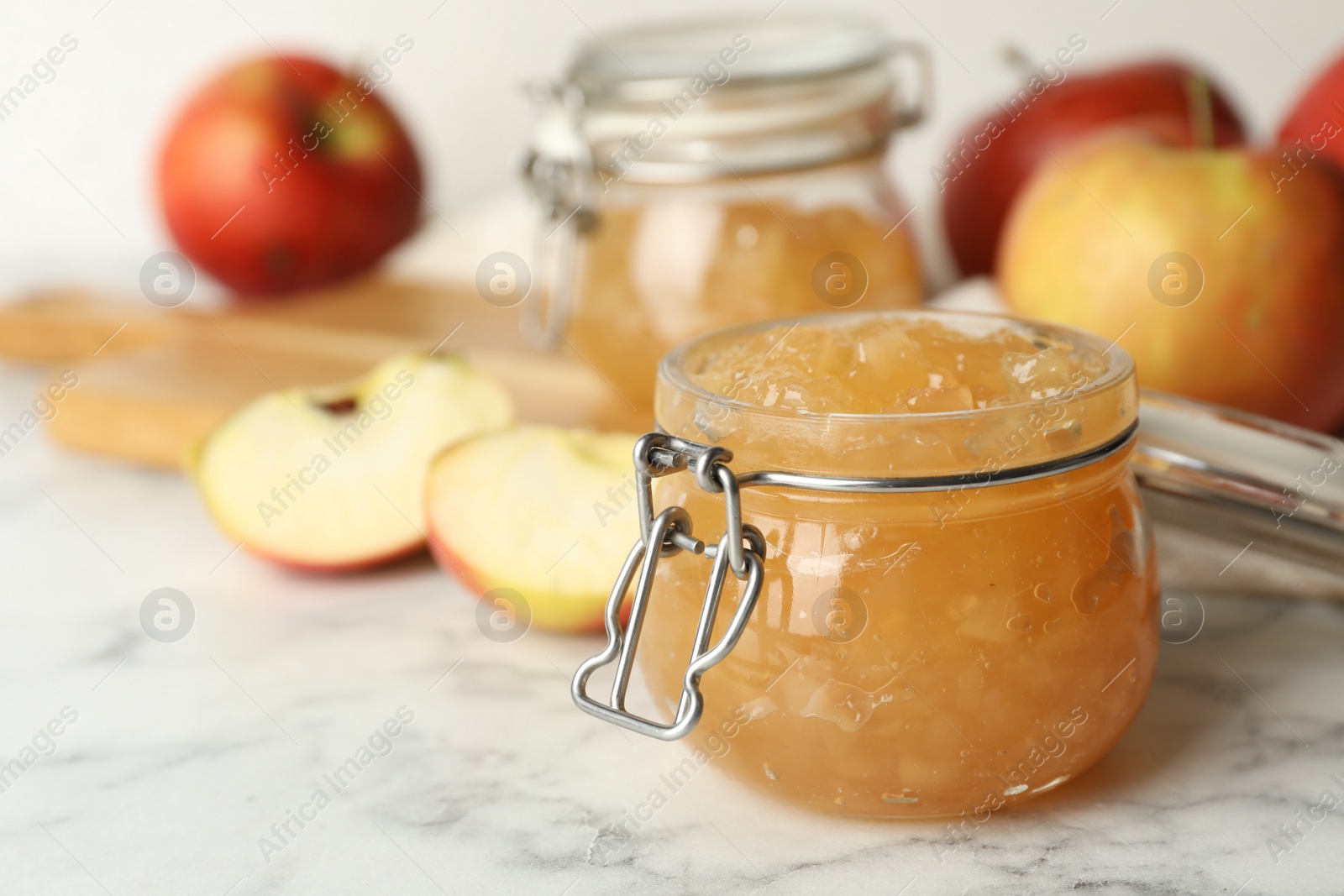 Photo of Delicious homemade apple jam on marble table