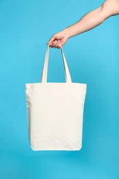 Young man with eco bag on blue background, closeup